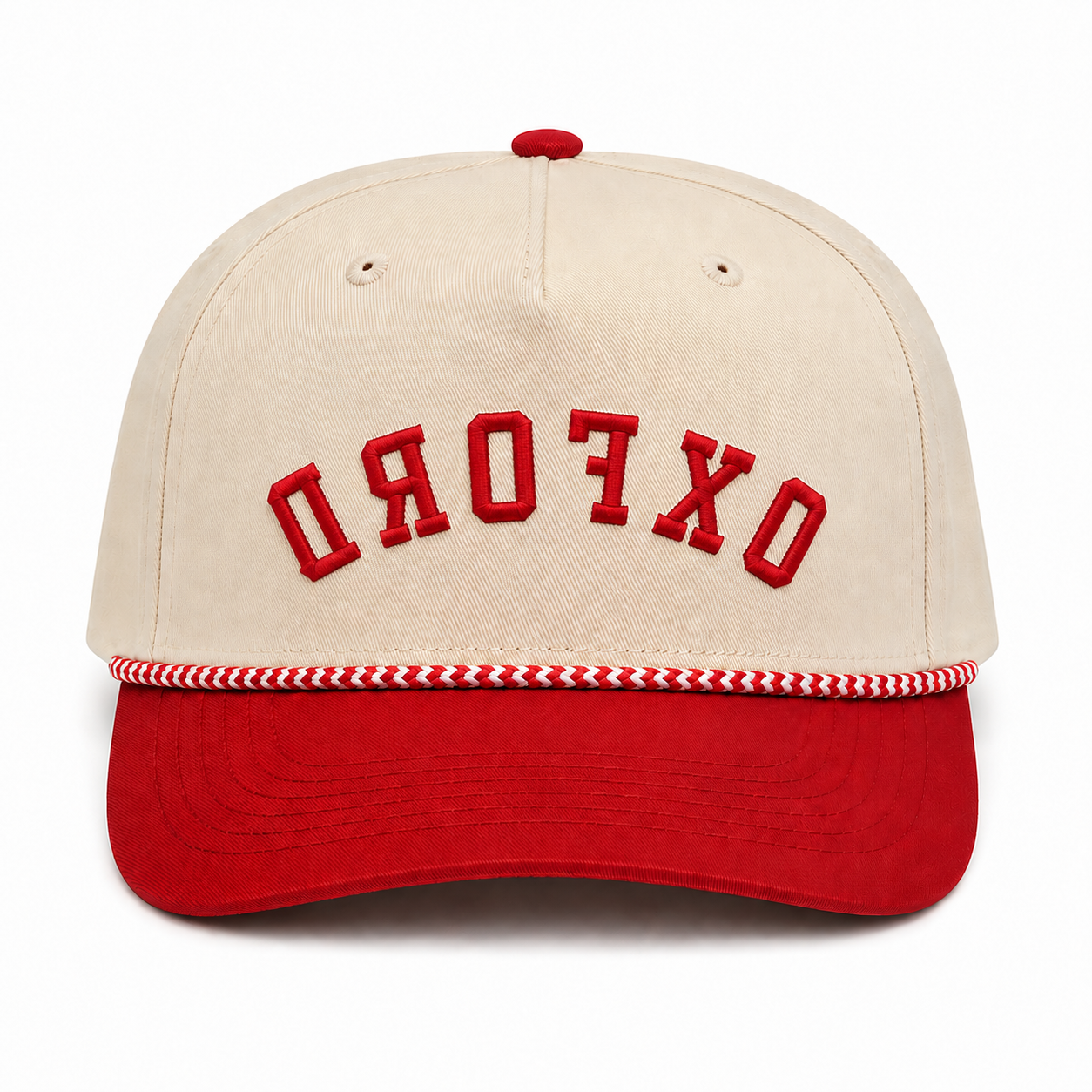 A structured baseball cap with a cream-colored crown and a red curved brim. The front of the crown features the word 'OXFORD' embroidered in red arched block letters, and a red and white braided trim runs horizontally around the edge of the brim.